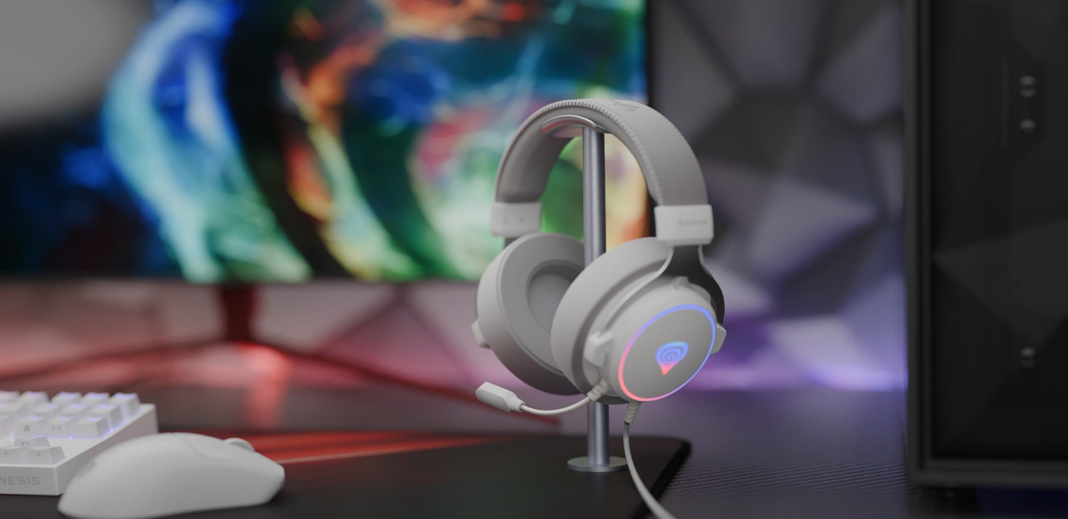 Bílá herní náhlavní souprava přes uši s osvětlením RGB a mikrofonem, zobrazená na stojanu na barevném pozadí.