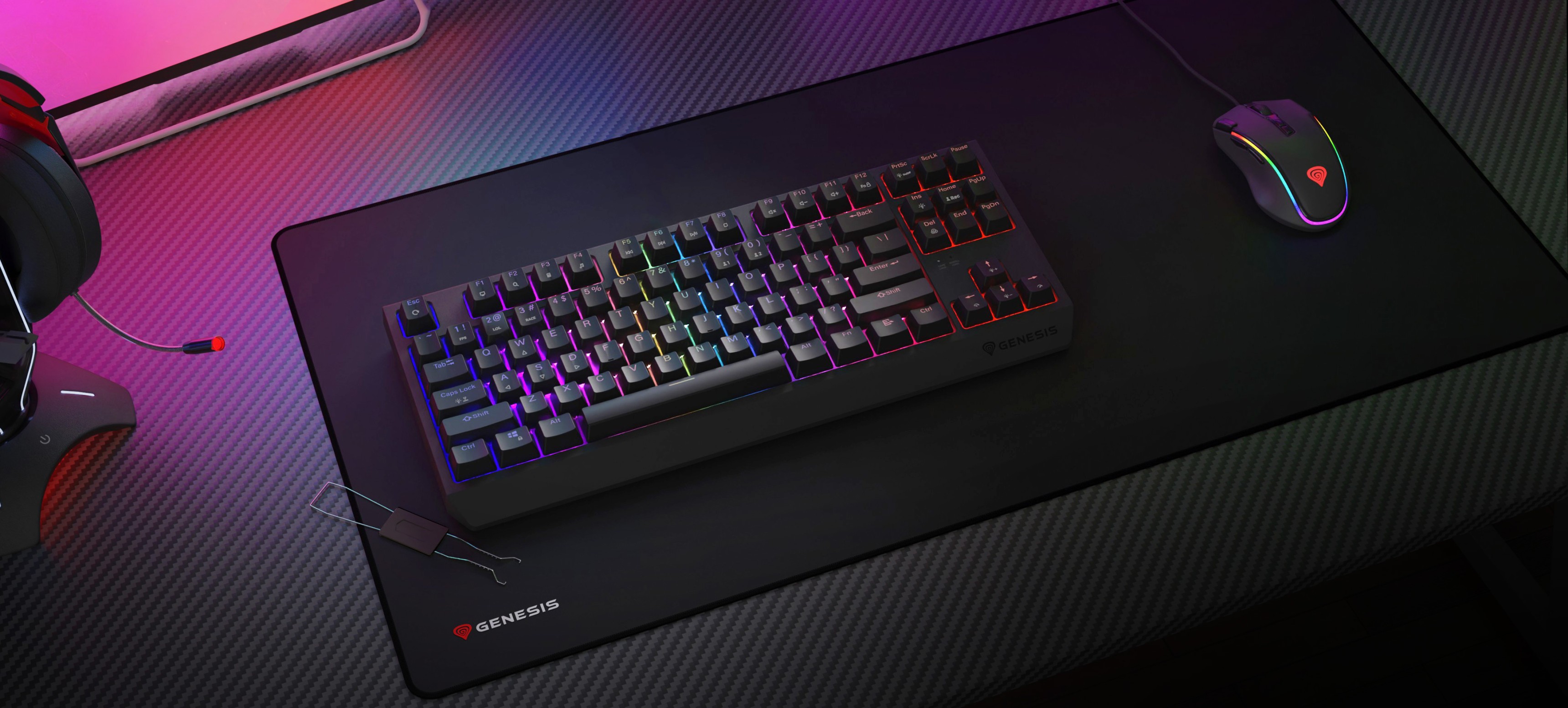 Bezdrátová mechanická herní klávesnice s osvětlením RGB, umístěná na velké podložce pod myš vedle herní myši a náhlavní soupravy.